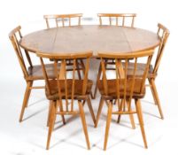 An Ercol elm and beech circular folding dining-table and six spindle back dining chairs,