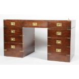 A reproduction mahogany and brass banded campaign style desk, inset with distressed leather top,