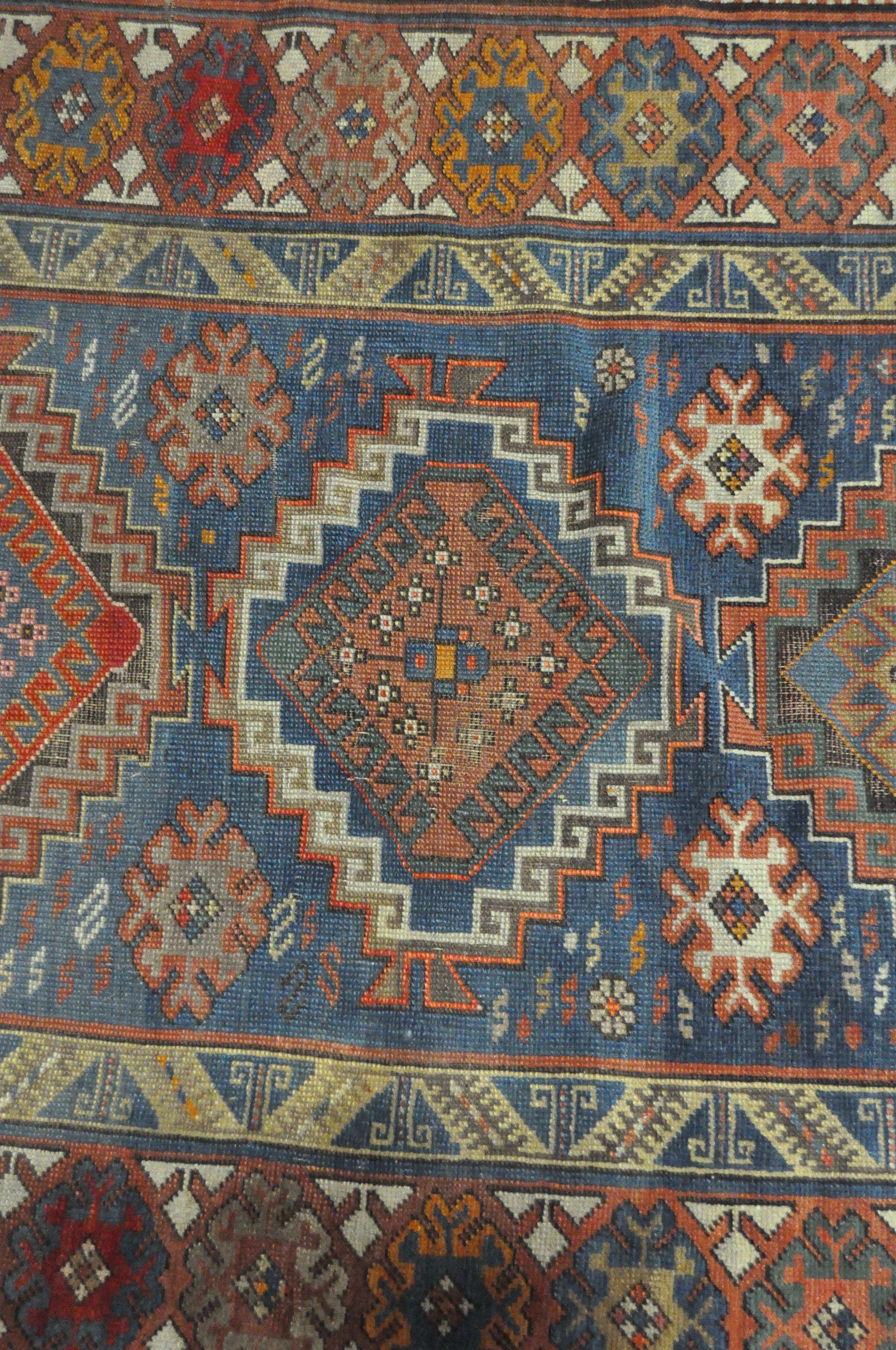 A 20th century Kazak style wool rug, woven with geometric lozenges on a blue ground with red border, - Image 12 of 13