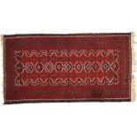 An Iranian wool rug, 20th century, red ground woven with bands of geometric ornament,