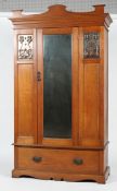 An Art Nouveau oak wardrobe, inset with two foliate copper panels flanking a central mirror,