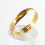A yellow metal 3.50mm flat profile wedding ring. Hallmarked 22ct gold, Birmingham. Size P