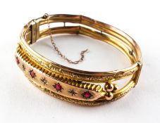 A yellow metal bangle set with synthetic rubies and rose cut diamonds.