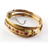 A yellow metal bangle set with synthetic rubies and rose cut diamonds.