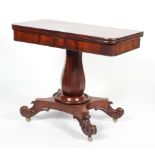 A William IV mahogany fold over top tea table on baluster column stem and four scroll legs