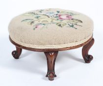 A Victorian walnut low circular footstool, with floral tapestry cover above cabriole legs,