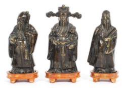 Three Chinese bronze figures of Immortals, on wooden stands, 20th century,