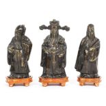 Three Chinese bronze figures of Immortals, on wooden stands, 20th century,