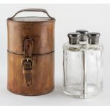 An Edward VII Campaign style leather cased travelling set of three silver mounted glass bottles,