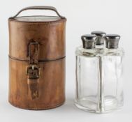 An Edward VII Campaign style leather cased travelling set of three silver mounted glass bottles,