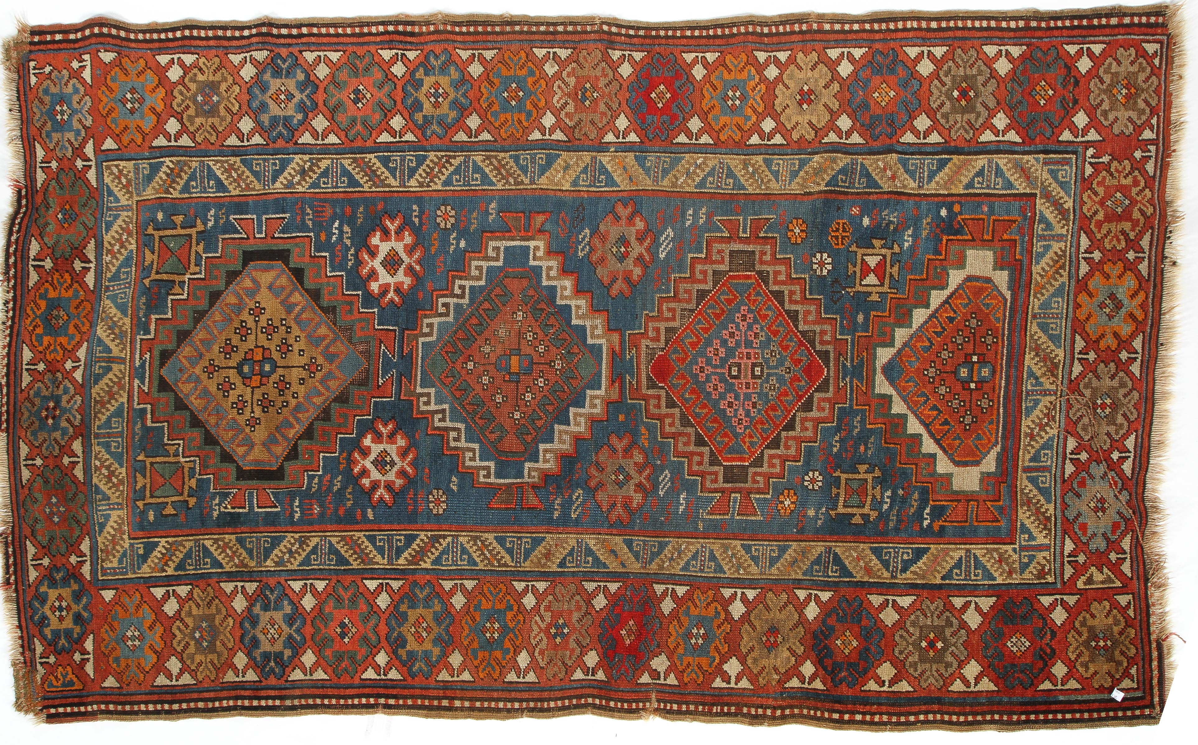 A 20th century Kazak style wool rug, woven with geometric lozenges on a blue ground with red border,