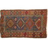 A 20th century Kazak style wool rug, woven with geometric lozenges on a blue ground with red border,