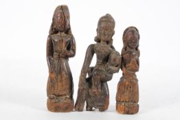 Three Eastern carved wooden figures, possibly Chinese, including one holding a young child,