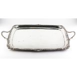A George V silver tray, of two handled rectangular form with gadrooned borders and shell highlights,