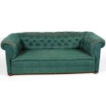 A Victorian button-back Chesterfield sofa, upholstered in dark green damask fabric, on bun feet,