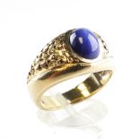 A yellow metal ring set with an oval cabochon synthetic star sapphire. No hallmark - stamped 10K.