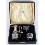 A George V cased silver four piece cruet set, of hexagonal form with blue glass liners,