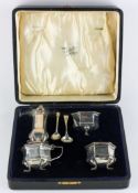A George V cased silver four piece cruet set, of hexagonal form with blue glass liners,