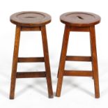 A pair of 20th century oak stools, with recessed circular seats on four chamfered splayed legs,