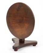 A mahogany miniature or apprentice tilt top table on a tripod base and bun feet,