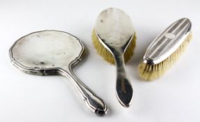 A silver backed dressing table mirror (lacking glass), a handled brush and a clothes brush,