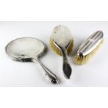 A silver backed dressing table mirror (lacking glass), a handled brush and a clothes brush,