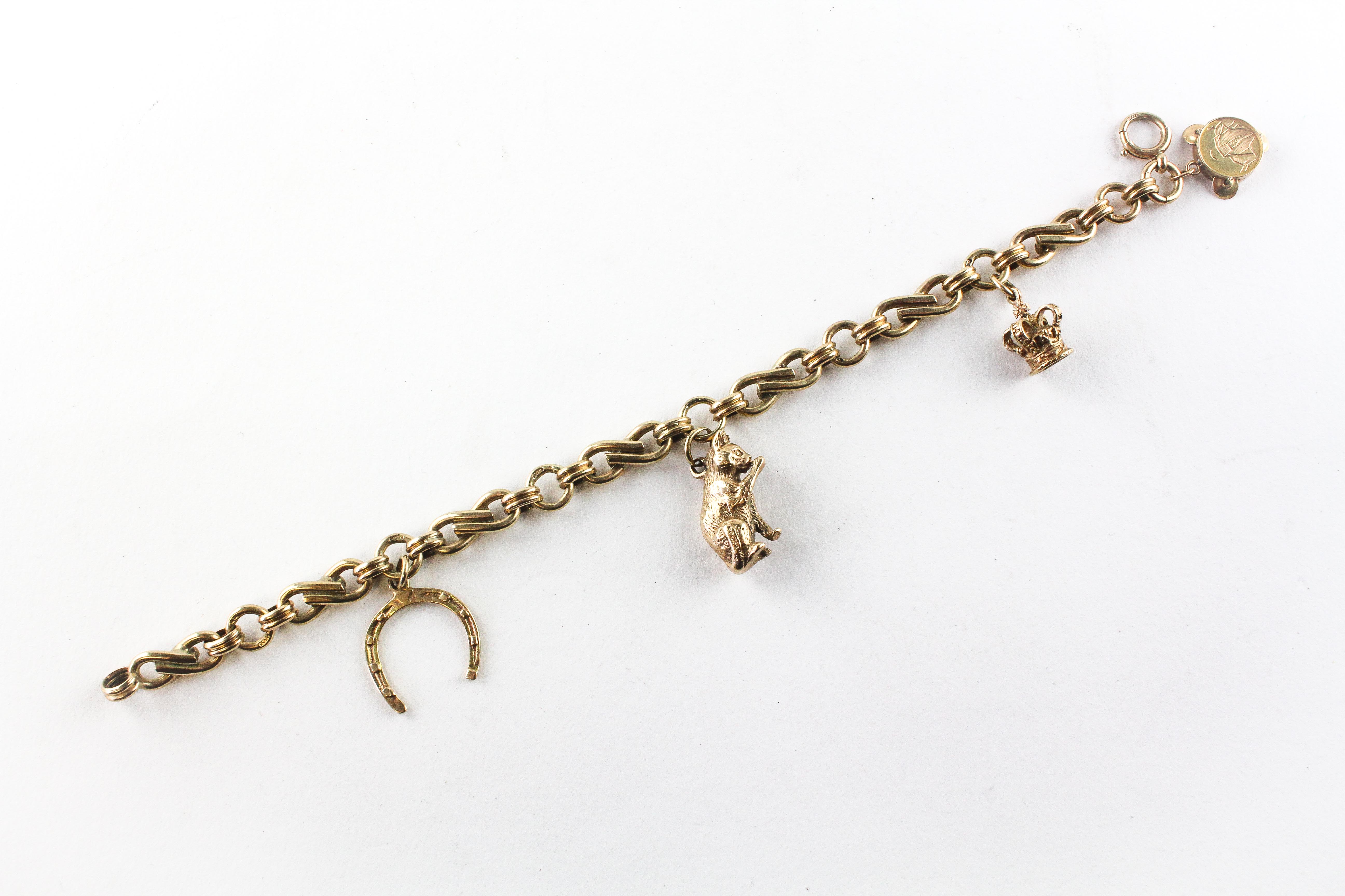 A yellow metal abstract link bracelet fitted with four assorted charms. Hallmarked 9ct gold.