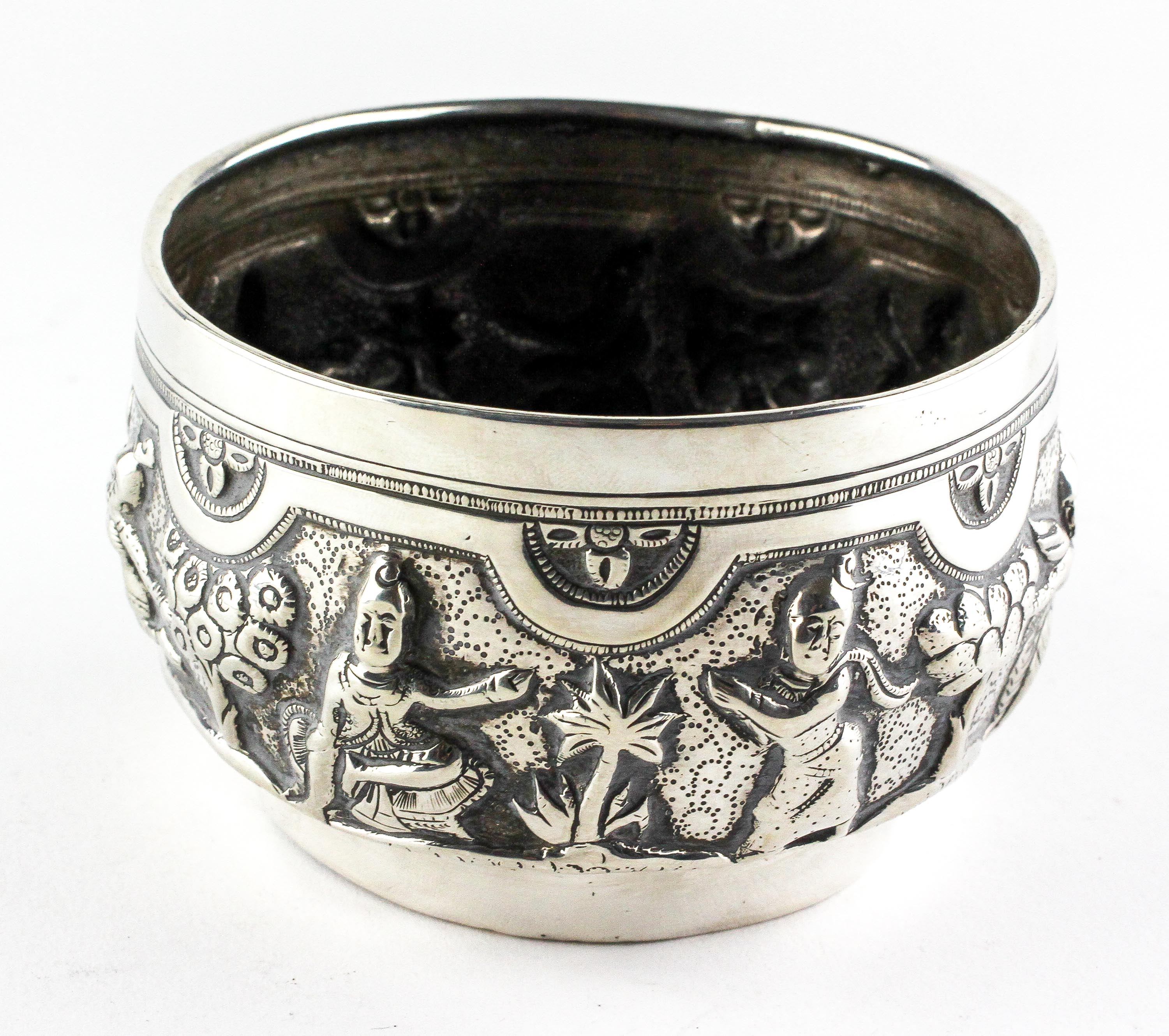 An Indian white metal bowl, late 19th or 20th century, embossed with figures and plants,