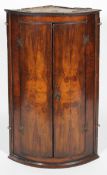 A 19th century walnut corner cupboard, of D-shape section, revealing three shelves,