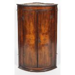 A 19th century walnut corner cupboard, of D-shape section, revealing three shelves,