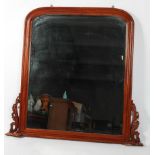 A mahogany overmantel mirror, the arched plate supported by scrolling foliate brackets,