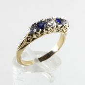 A yellow metal carved half hoop ring set with two sapphires and three diamonds.