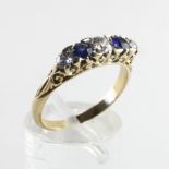 A yellow metal carved half hoop ring set with two sapphires and three diamonds.