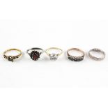 A collection of five rings to include: A silver garnet cluster ring; An emerald half hoop ring;