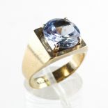 A yellow metal ring set with a 10mm round cut synthetic blue spinel.