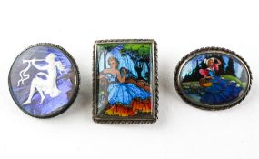 A collection of three brooches each depicting portraits.