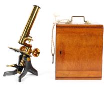 An Edwardian brass microscope in wooden travelling box, with associated fittings and lenses,