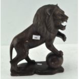 A carved wooden lion with a paw on a ball,