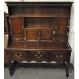 An oak dresser, three tiered with three cupboards and two drawers, brass hinges and handles,
