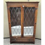 An oak glazed display cabinet with carved Gothic detailing,