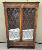 An oak glazed display cabinet with carved Gothic detailing,