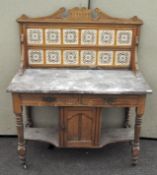 A marble top washstand with ceramic tile back, two short drawers over a single door cupboard,