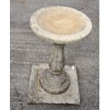 A cast stone bird bath with circular top