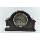 An oak cased mantle clock, the dial with Arabic numerals denoting hours,