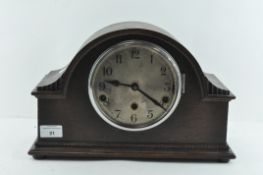 An oak cased mantle clock, the dial with Arabic numerals denoting hours,