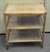 A three tier wooden drinks trolley on metal wheels, height 74cm,