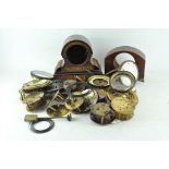 A collection of clock parts, including movements, cases and dials,