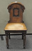 A Victorian oak hall chair, with a carved scroll and crest to the back, raised on turned legs,