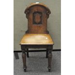 A Victorian oak hall chair, with a carved scroll and crest to the back, raised on turned legs,