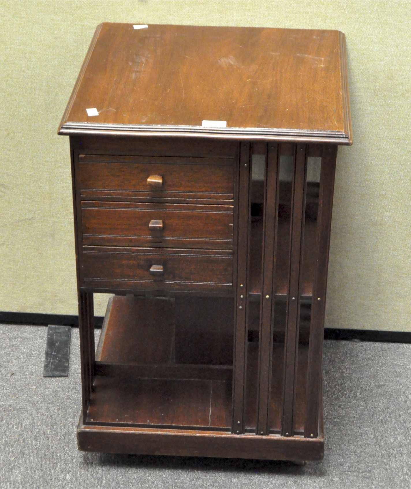 A mahogany revolving bookcase, with three drawers to one side,